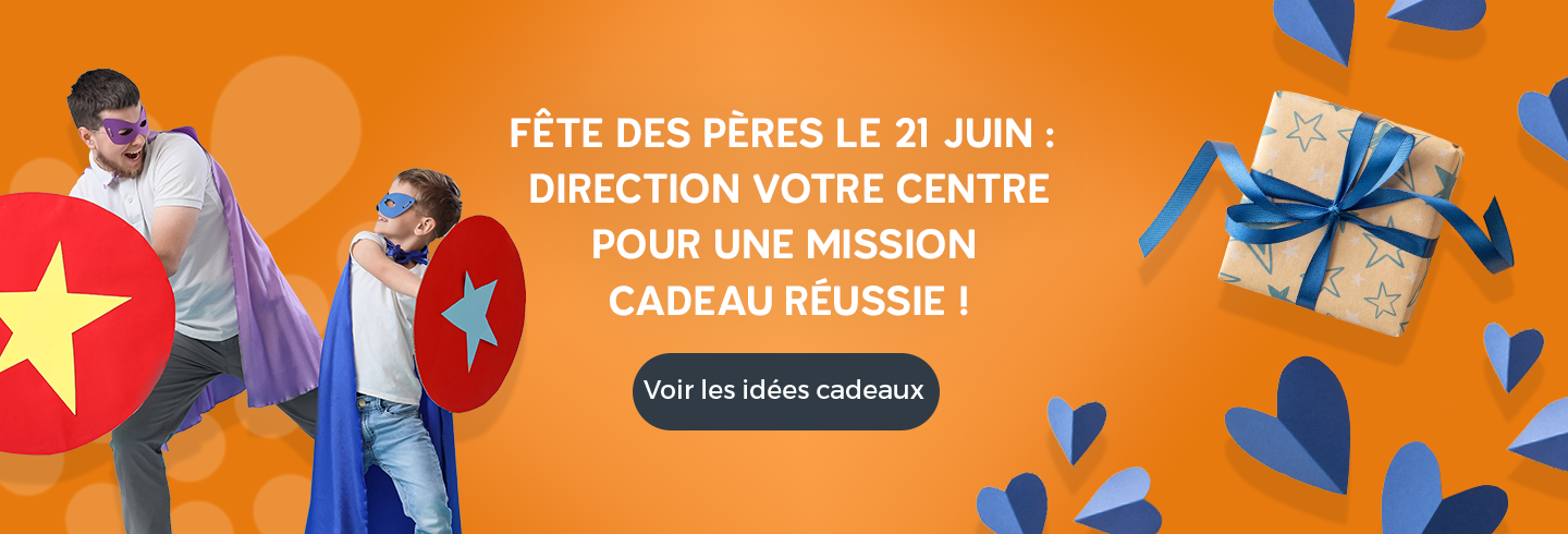 Bannière Fête des Pères : un père et son enfant déguisés en super-héros avec cape, masque et boucliers, sur un fond orange, avec le texte « Fête des pères le 21 juin : direction votre centre pour une mission cadeau réussie ! », des cœurs décoratifs et un cadeau emballé.